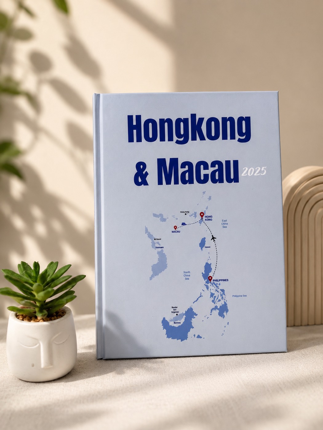 Light blue hardbound photobook titled Hongkong and Macau 2025 with a map illustration